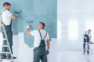 3 men painting grey color in interior wall of the house.