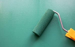 painting wall with green color through roller brush