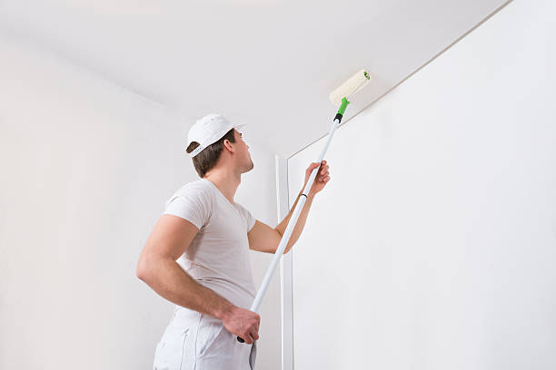 professional painter in white uniform painting wall with white color